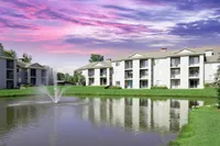 Clearview Apartments in Holland, MI Charming apartment complex, Clearview Apartments, with serene pond view, vibrant sunset skies, and lush green surroundings.