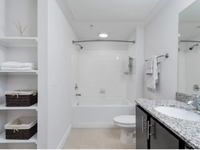 Bathroom at The Melrose Apts in Nashville, Tennessee. Elegant bathroom featuring a sleek granite countertop, spacious bathtub, and built-in shelving with tasteful storage baskets at The Melrose Apts in Nashville Tennessee.