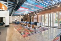 Apt CoWork at The Melrose Modern co-working space with vibrant, colorful ceiling panels and stylish furnishings, featuring open workstations and large windows for natural light at The Melrose Apartments in Berry Hill.