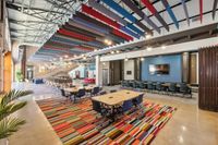 Apt CoWork at The Melrose Apartments in Nashville, TN. A vibrant co-working space featuring colorful ceiling panels, contemporary furnishings, and an open layout that encourages creativity and collaboration.