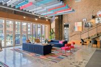 Be inspired by the vibrant colors of this stylish coworking space with playful decor at Apt CoWork at The Melrose Vibrant modern lounge with plush seating, colorful decor, and large windows overlooking a pool area at The Melrose Apartments in Nashville.