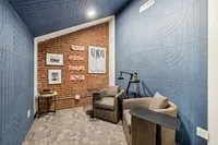 Podcast Studio at The Melrose Apartments Cozy and stylish podcast studio with modern blue acoustic panels and a warm brick accent wall, featuring comfortable seating and contemporary artwork at The Melrose Apts in Nashville, TN.