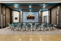 Conference Room at The Melrose Apartments in Berry Hill, TN Elegant conference room featuring stylish teal chairs arranged in a semicircle, a large flat-screen display, and sophisticated wall paneling at The Melrose Apartments in Berry Hill, TN.