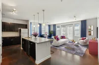 Cozy 2 Bedroom Apartment Living Room at The Melrose in Nashville, TN Modern open-concept 2 bedroom living space featuring a stylish kitchen island, elegant dining area, and cozy living room with vibrant decor and natural light at The Melrose Apartments in Nashville,TN.
