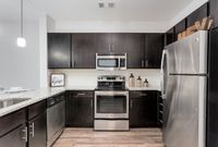 The Melrose Apartments in Nashville offer modern kitchens with sleek finishes, contemporary design, and stainless steel appliances. Sleek modern kitchen featuring dark cabinetry, stainless steel appliances, and elegant granite countertops at The Melrose Apartments in Nashville.