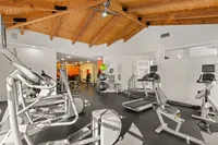 Modern fitness center at Pavilions Apartments with state-of-the-art gym equipment under a warm, vaulted wooden ceiling.