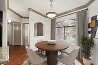 Elegant dining area featuring a round wooden table, plush chairs, and large window with natural light at Pavilions Apartments.