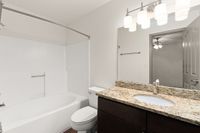 Contemporary bathroom at Pavilions Apartments with elegant granite countertop, built-in bathtub, and stylish lighting fixtures.