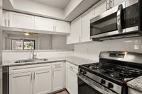 Modern kitchen at Pavilions Apartments with sleek stainless steel appliances, elegant granite countertops, and white cabinetry offering abundant storage space.