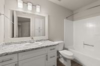 Contemporary bathroom at Pavilions Apartments design featuring sleek granite countertops, bright vanity lighting, and a modern bathtub.