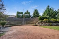 Amphitheater Charming outdoor amphitheater at Scott Mountain Apartments with tiered stone seating, surrounded by lush greenery and blue skies, perfect for community gatherings.