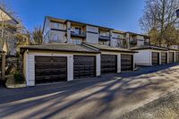 1, 2, 3 Bedroom Apartments in Portland, OR Charming apartment complex, Scott Mountain, with modern garages, surrounded by serene trees under a clear blue sky.