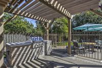 Poolside Grilling Charming outdoor patio at Scott Mountain Apartments with elegant pergola, stylish grill, and cozy dining area with vibrant umbrellas.