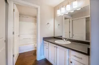 Renovated Bathroom Bright and elegant bathroom at Scott Mountain Apartments with white cabinetry, a large mirror, and modern lighting fixtures.