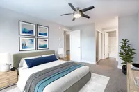 Renovated Bedroom Modern bedroom at Scott Mountain Apartments with cozy ambiance, featuring a plush bed, abstract wall art, and a ceiling fan for comfort.