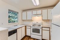 Classic Kitchen Bright and modern kitchen at Scott Mountain Apartments with sleek white cabinetry, stainless steel appliances, and a scenic window view offering natural light.