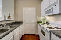 Modern kitchen at Stonebriar of Frisco Apartments with sleek granite countertops, white cabinetry, and built-in appliances for a stylish and functional space.