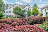 Exterior of Summer Park Apartments, a charming apartment complex with lush landscaping, vibrant flowers, and elegant architecture under a clear blue sky.