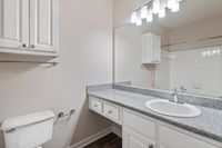 Elegant bathroom at Summer Park Apartments featuring a sleek granite countertop, stylish vanity with ample storage, and a large mirror reflecting modern lighting.