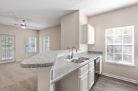 Bright open kitchen at Summer Park Apartments with modern countertops and a spacious living area, featuring large windows and elegant fixtures.