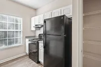 Modern kitchen featuring sleek black appliances, white cabinetry, and sunlit ambiance with ample pantry space at Summer Park Apartments.