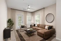 Elegant living room at Summer Park Apartments featuring a cozy brown sectional, plush area rug, and a stylish coffee table, with natural light streaming through large windows.