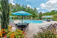 Charming outdoor pool area with lush greenery, inviting poolside loungers, and vibrant umbrellas creating a serene oasis at Summer Park Apartments.