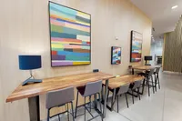 Apt CoWork Community Workspace at Sugarmont Apartments in Salt Lake City Modern workspace with sleek wooden tables, stylish chairs, and vibrant abstract art on walls, perfect for a creative atmosphere at Apt CoWork at Sugarmont Apartments in Salt Lake City