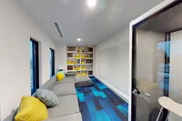 Apt CoWork Privacy Pod at Sugarmont Apartments in Salt Lake City Modern apartment lounge with cozy gray sectional, vibrant yellow and blue accents, and chic built-in bookshelves at Apt CoWork at Sugarmont Apartments in Sugar House
