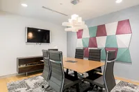 Apt CoWork Conference Room Setup at Sugarmont Apartments in Salt Lake City Modern conference room featuring a sleek wooden table, executive leather chairs, geometric wall art, and ambient lighting perfect for productive meetings at Apt CoWork at Sugarmont Apartments in SLC