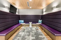 Apt CoWork Conference Room with TV at Sugarmont Apartments in Salt Lake City Modern conference room with plush purple seating, sleek tables, and a stylish patterned rug under warm ambient lighting at Apt CoWork at Sugarmont Apartments in Salt Lake City
