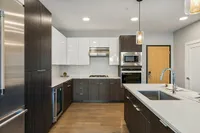 Sugarmont-Townhome-Kitchen-in-Sugar-House-Utah Modern kitchen townhome featuring sleek dark wood cabinets, stainless steel appliances, and a spacious island with elegant pendant lighting at Sugarmont Apartments in Sugarhouse Utah
