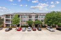 Toscana at Valley Ridge Apartments in Lewisville, TX Charming three-story residential building, Toscana at Valley Ridge Apartments, with modern architecture, ample parking, and lush greenery under a bright blue sky.