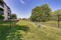 Toscana at Valley Ridge's Pet Friendly Perks: Dog Park Spacious landscaped dog park with modern apartment building and secure fencing, perfect for pet-friendly outdoor enjoyment at Toscana at Valley Ridge Apartments.