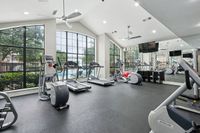 24-Hour Fitness Center at Toscana at Valley Ridge Spacious gym with large windows, featuring treadmills and elliptical machines, offering a vibrant workout environment with a pool view at Toscana at Valley Ridge.