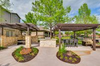Outdoor Entertainment Area Charming outdoor patio at Toscana at Valley Ridge Apartments with stone BBQ area, stylish pergola, and lush greenery, perfect for entertaining in a serene setting.
