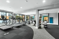 Modern fitness center with state-of-the-art gym equipment, including treadmills and exercise bikes, overlooking a pool through large windows at Cottonwood Westside Apartments in Midtown Atlanta