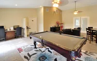 Chic recreational room at Camelot Apartments featuring a sleek pool table, comfortable seating area, and modern workspace, perfect for entertainment and productivity.