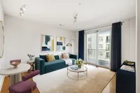 Cozy 1 bedroom living room at the Melrose Apartments in Nashville Modern living room at The Melrose Apartments with a chic teal sofa, vibrant artwork, and a cozy ambiance enhanced by natural light from large windows.