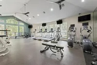 Spacious modern gym with abundant natural light, featuring treadmills, ellipticals, and exercise bikes  at Raveneaux Apartments in Houston Texas
