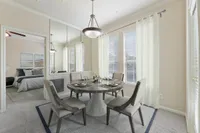 Elegant dining area with a contemporary round table, stylish chairs, and large windows offering natural light, adjacent to a cozy bedroom at Raveneaux Apartments in Houston