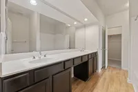 Elegant bathroom featuring a double sink vanity with modern fixtures, large mirror, and ample storage space at Raveneaux Apartments in Houston TX