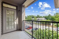 Charming balcony offering a picturesque view of lush greenery and a peaceful neighborhood street, enhanced by a bright, clear sk yat Raveneaux Apartments in Houston