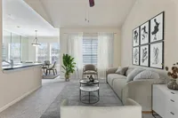 Bright and airy living room with modern decor, featuring a comfortable sofa, stylish wall art, and lush greenery, seamlessly connected to a well-lit dining area at Raveneaux Apartments in Houston