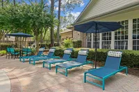 Charming outdoor area with cozy lounge chairs and umbrellas, perfect for relaxation amid lush greenery at Raveneaux Apartments in Houston TX