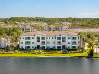 The-Marq-Highland-Park-Westchase-Tampa-FL-Apartments Charming lakeside apartment complex with palm trees and lush greenery, offering serene views and elegant architecture at the Marq Highland Park in Westchase