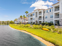 The-Marq-Highland-Park-Westchase-Lake-View-Tampa-Florida-Apartments Luxurious waterfront apartment complex with modern architecture and lush landscaping, featuring serene lake views and sunlit balconies at The Marq Highland Park in Westchase Tampa