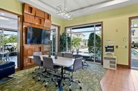 The Marq Highland Apartments Park Apt CoWork Community Workspace Westchase Tampa, FL Coworking space with modern decor, featuring a sleek conference table, large TV, and poolside views through expansive windows at Apt CoWork at The Marq Highland Park
