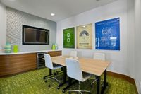 The Marq Highland Apartments Park Apt CoWork Rentable Conference Room in Westchase Tampa, FL Chic modern rentable conference room with stylish wall art, a sleek TV, and comfortable white seating around a wooden table at Apt CoWork at The Marq Highland Park in Westchase Tampa