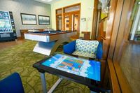 The Marq Highland Apartments Park Apt CoWork Gaming Area in Westchase Tampa, FL Luxurious recreation room featuring a modern pool table, vibrant lounge chairs, and an interactive gaming table, perfect for relaxation and entertainment at Apt CoWork at The Marq Highland Park in Westchase FL
